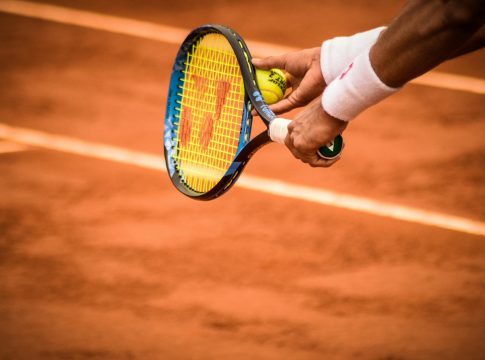 Close-Up Photo of Person Holding Tennis Racket and Ball