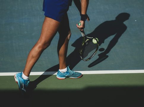 woman holding tennis ball and racket